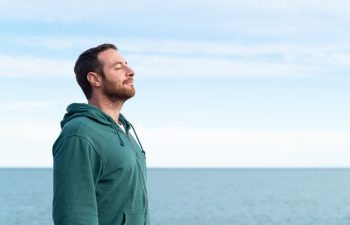 Relaxed man breathing fresh air with the sea at the background.