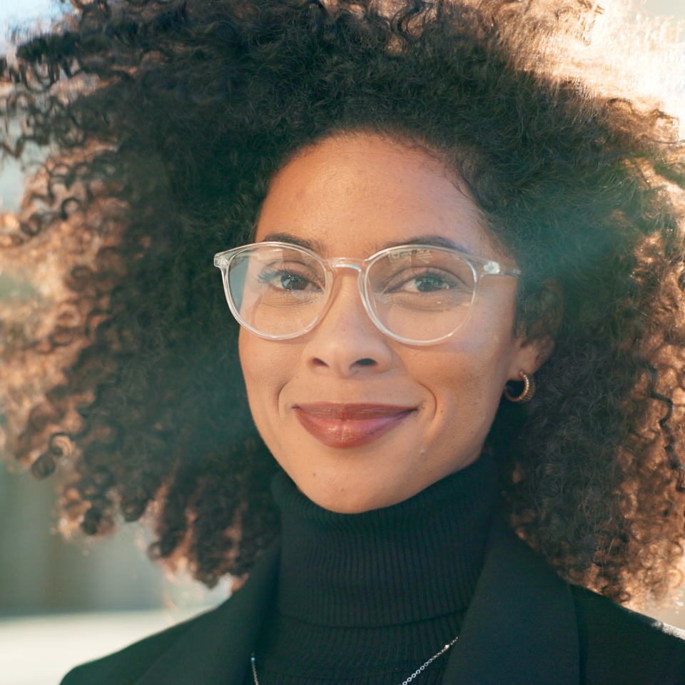 Face, city and woman with glasses, business and smile with professional, lens flare and career. Portrait, happy person and entrepreneur with eyewear, sunshine and clear vision with employee outdoor