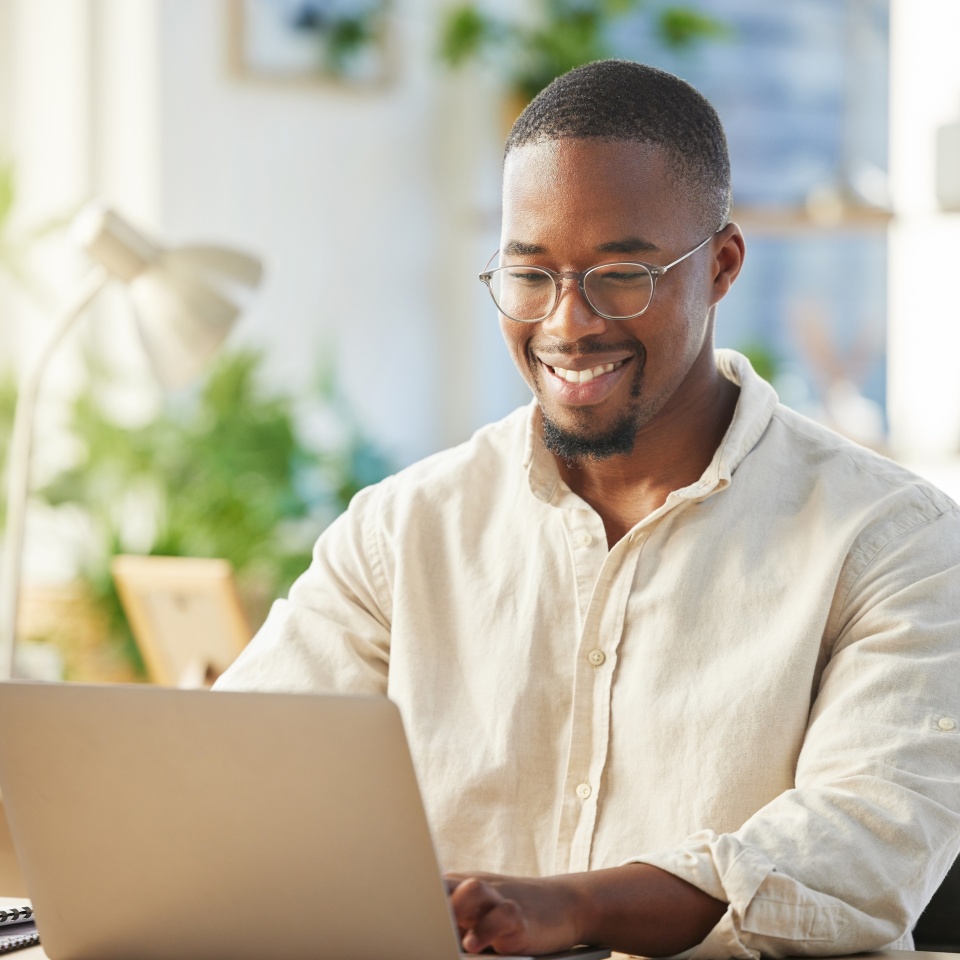 Black business man, startup and typing with laptop, smile and happy with web design, planning or development. African developer, businessman or entrepreneur with computer for coding in modern office