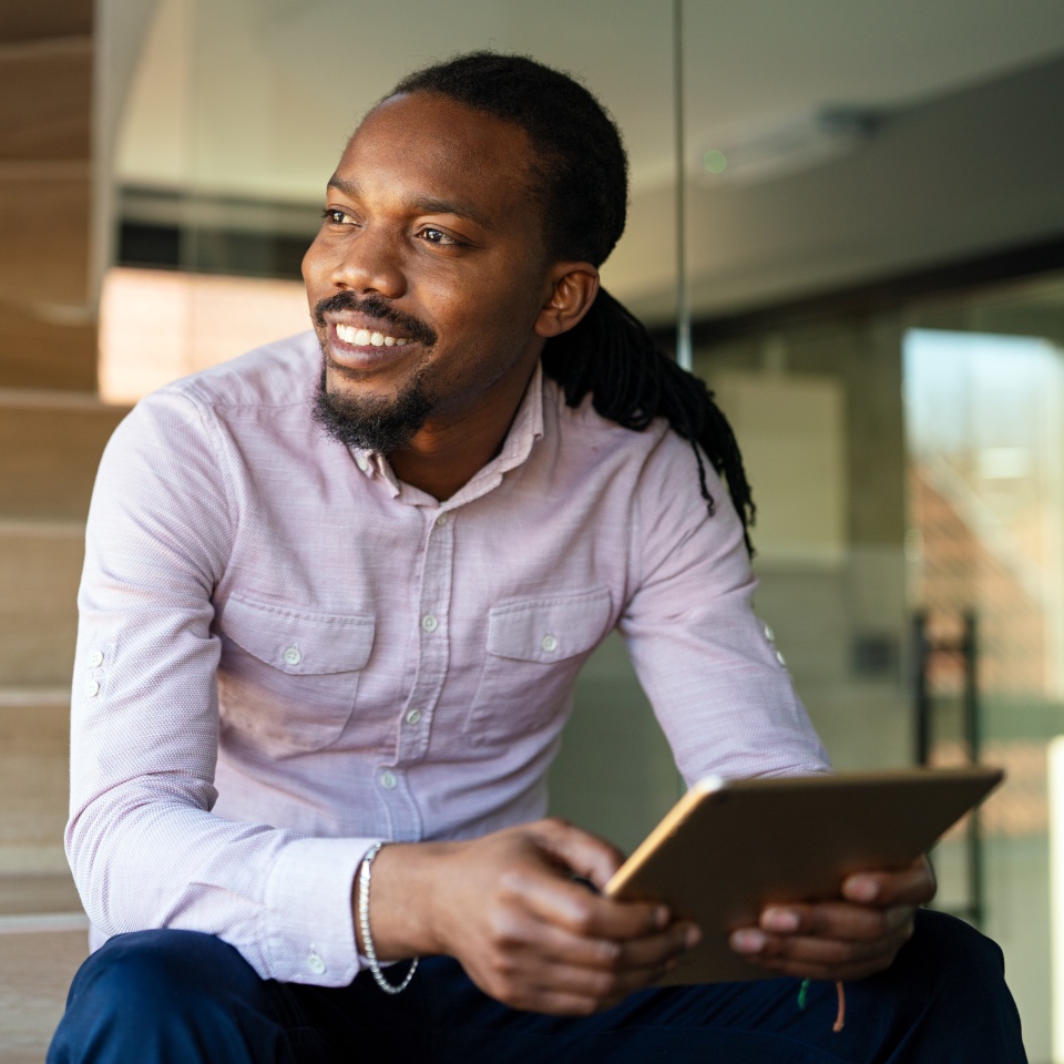 Relaxed smiling african american man holding digital tablet computer using apps