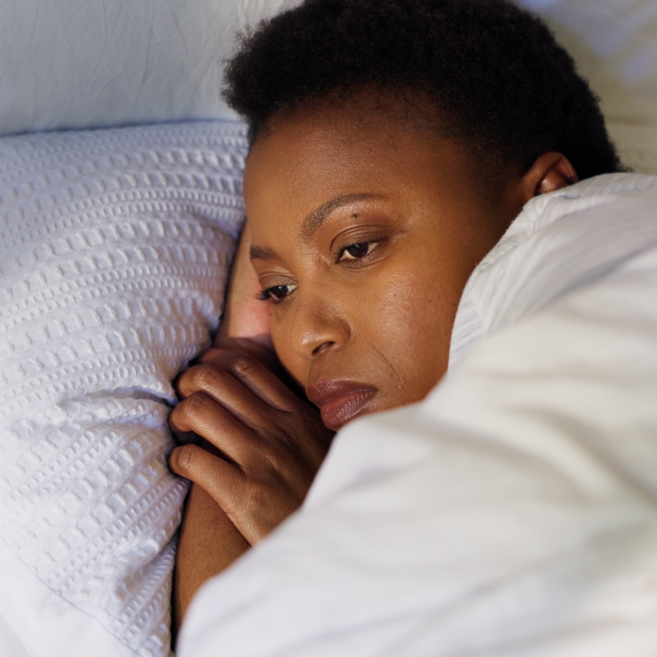 Thinking, woman and sleepless on bed, stress or anxiety for unemployment, fired or bedroom at night. Contemplating, jobless or black person with insomnia in home, late and worry for rent in apartment