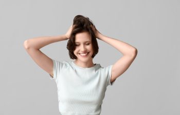 Beautiful young happy woman with bob hairstyle on grey background